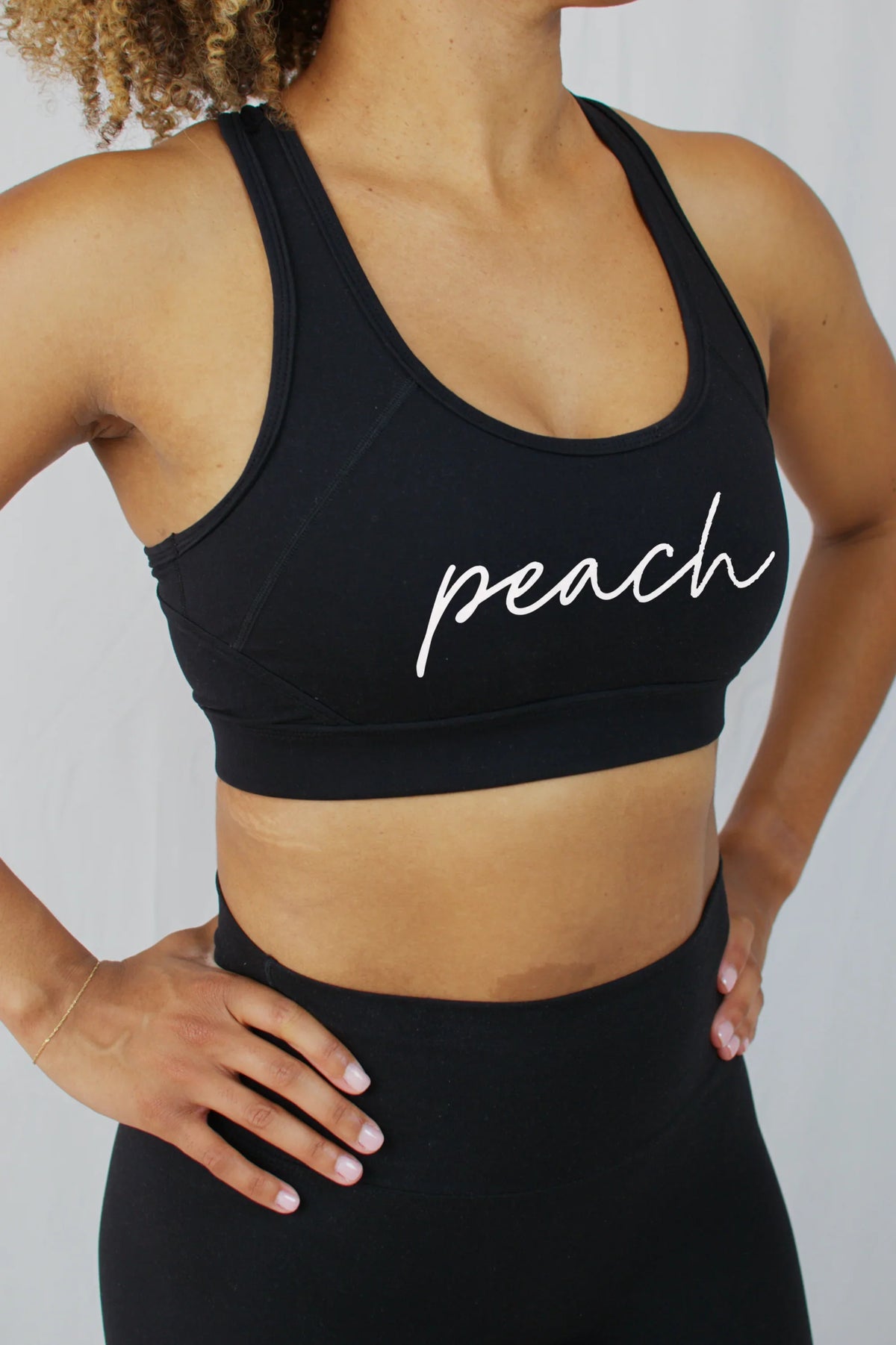 Woman wearing Peach Active black sports bra with logo, stylish athletic wear for women