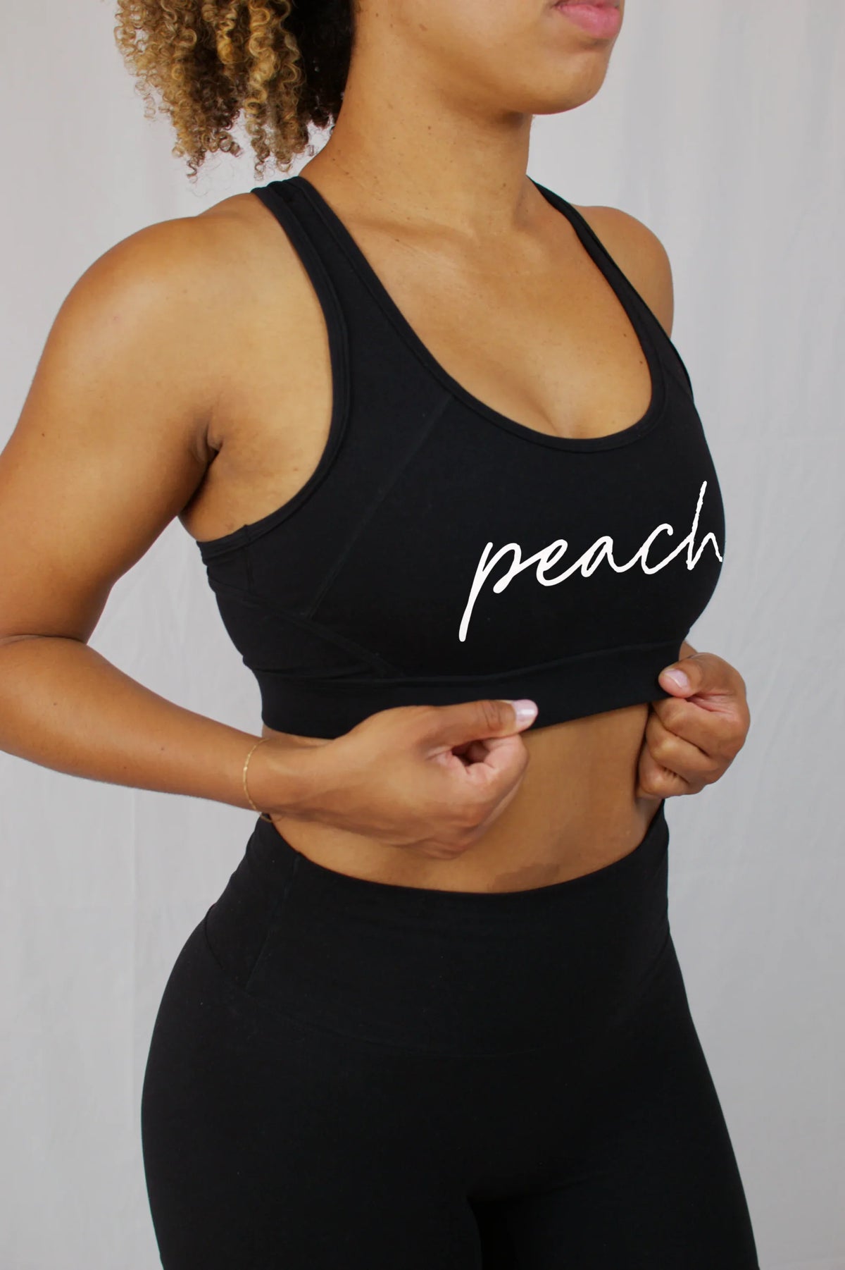 Woman wearing Peach Active black sports bra and leggings, showing athletic wear style