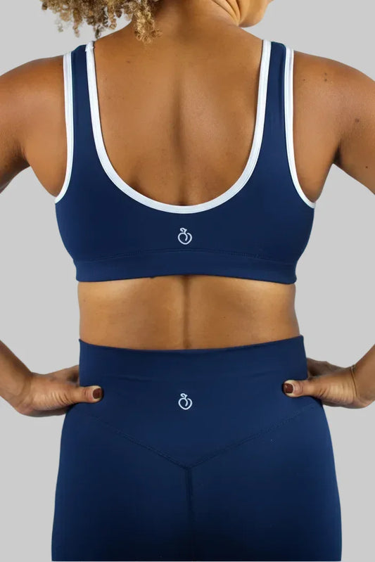 Person wearing a blue sports bra and leggings with a white logo on a light gray background