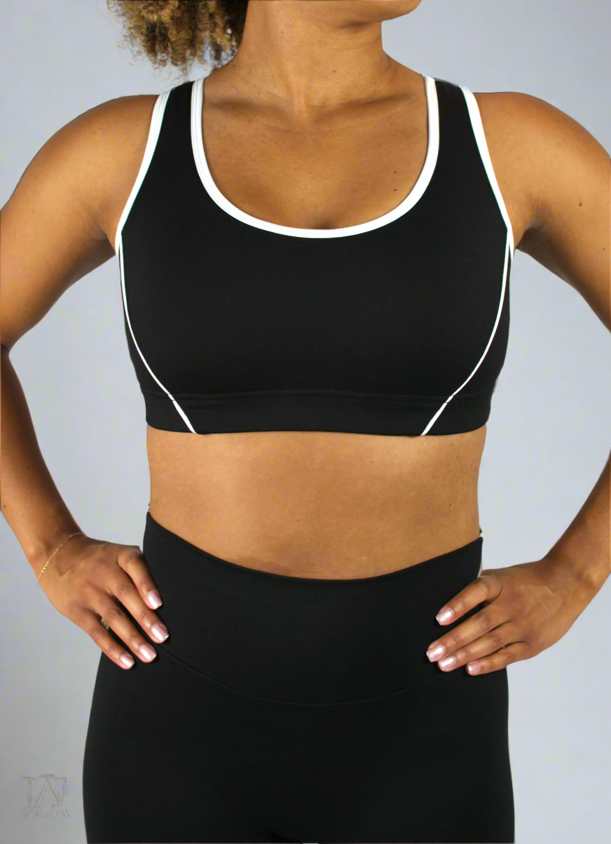Person wearing a black sports bra with white trim on a plain background