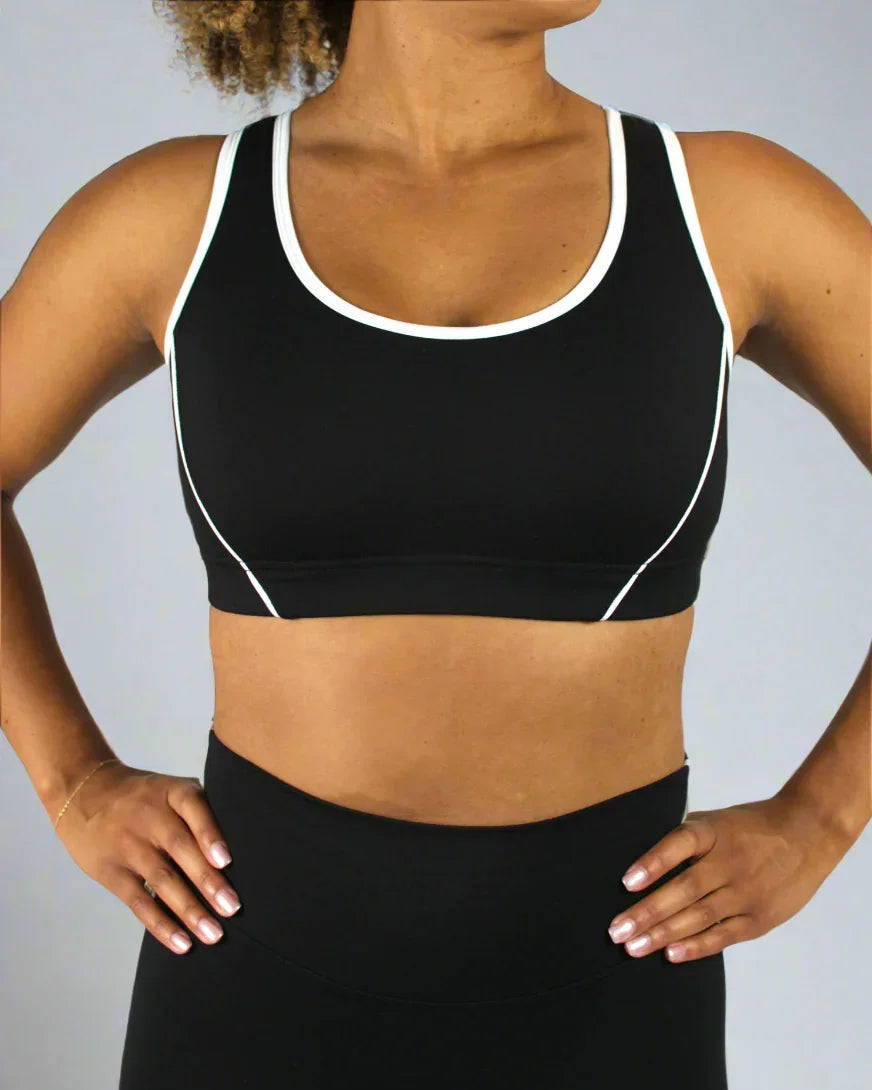Person wearing a black sports bra with white trim on a plain background