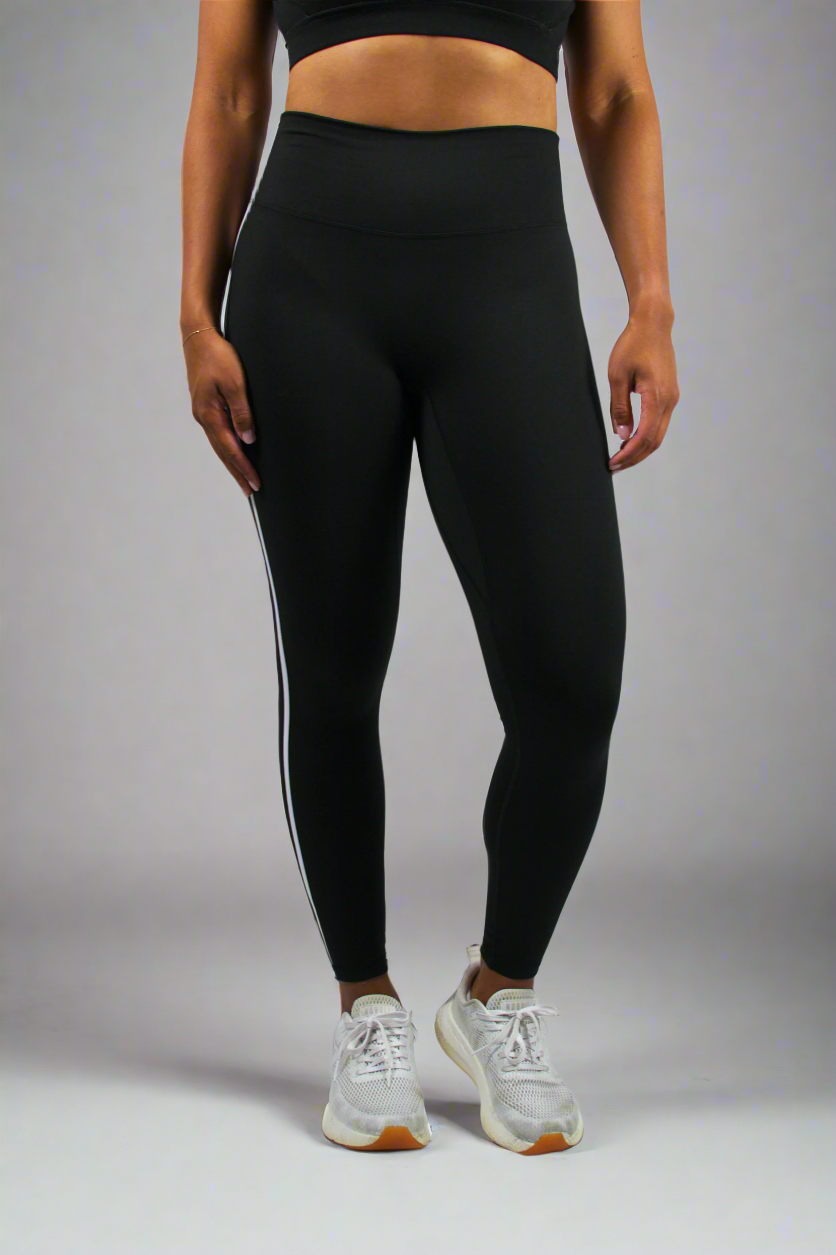 Person wearing black leggings with white stripes on a white background