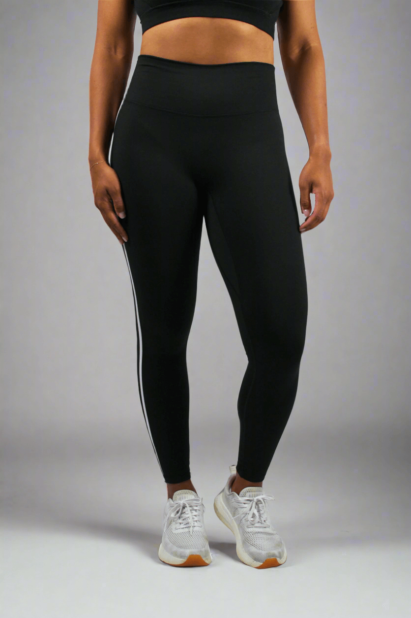 Person wearing black leggings with white stripes on a white background
