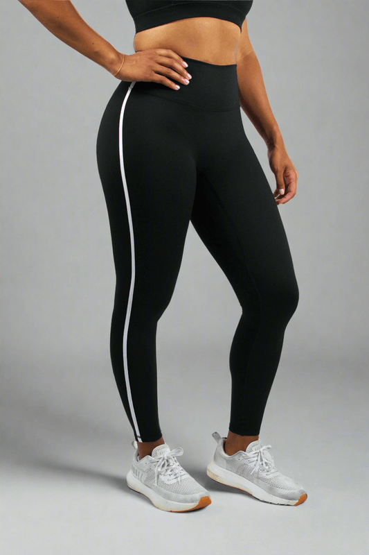 Person wearing black leggings with white stripes on a white background