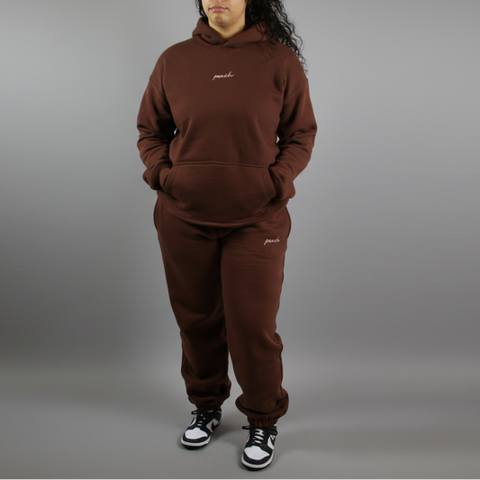 Person wearing a brown tracksuit with 'paul' branding on a white background
