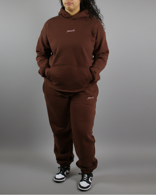 Person wearing a brown tracksuit with 'paul' branding on a white background