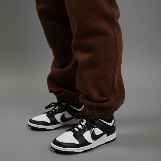 Black and white sneakers with brown pants on a light gray background