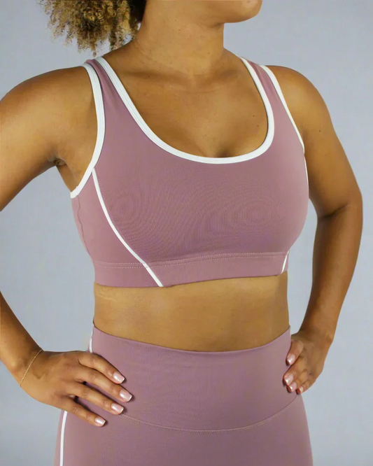 Person wearing a mauve sports bra and leggings set on a plain background