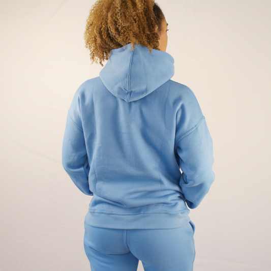 Person wearing a blue hoodie and pants on a plain background