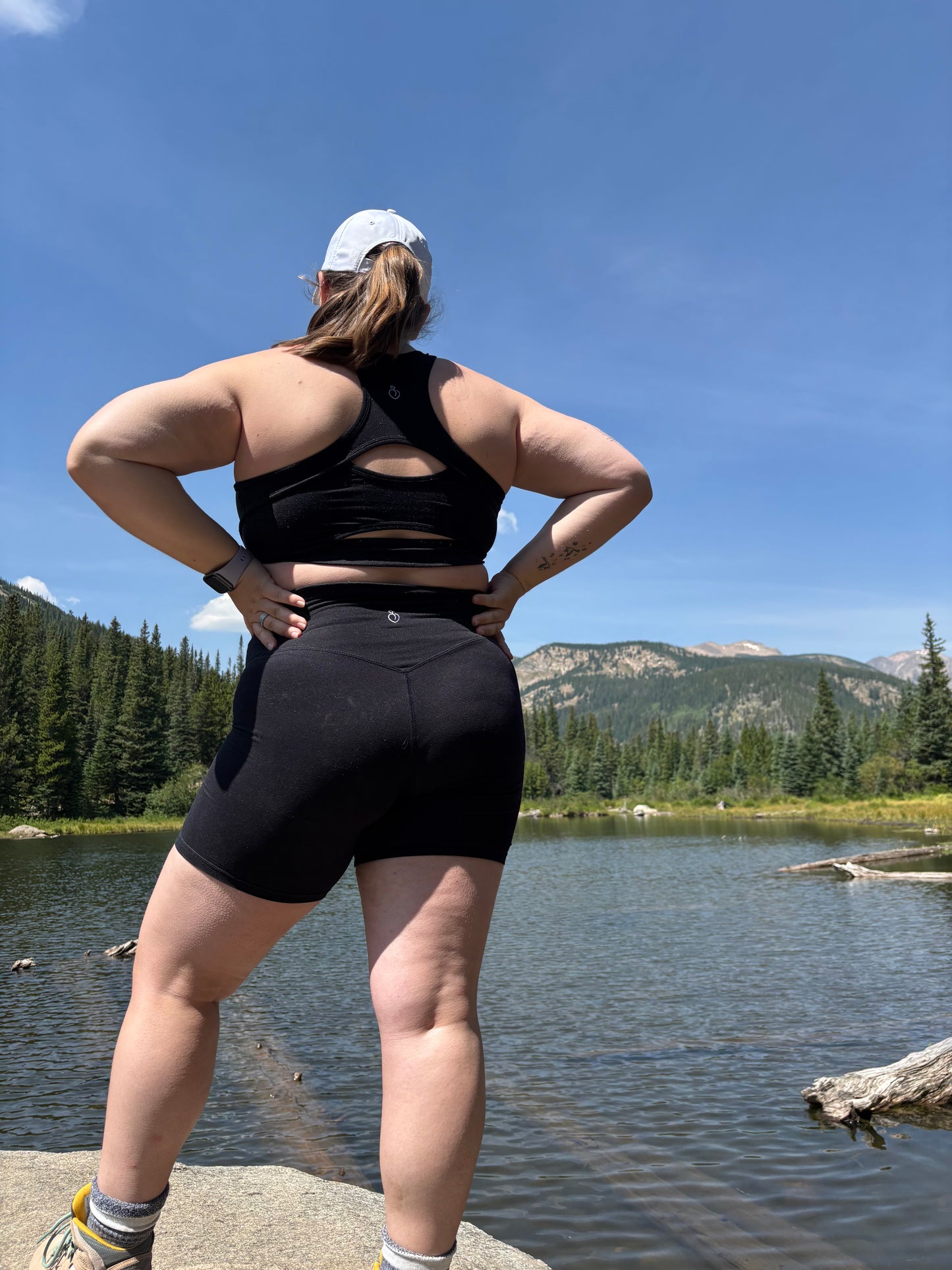 Person stretching outdoors by a lake with mountains in the background