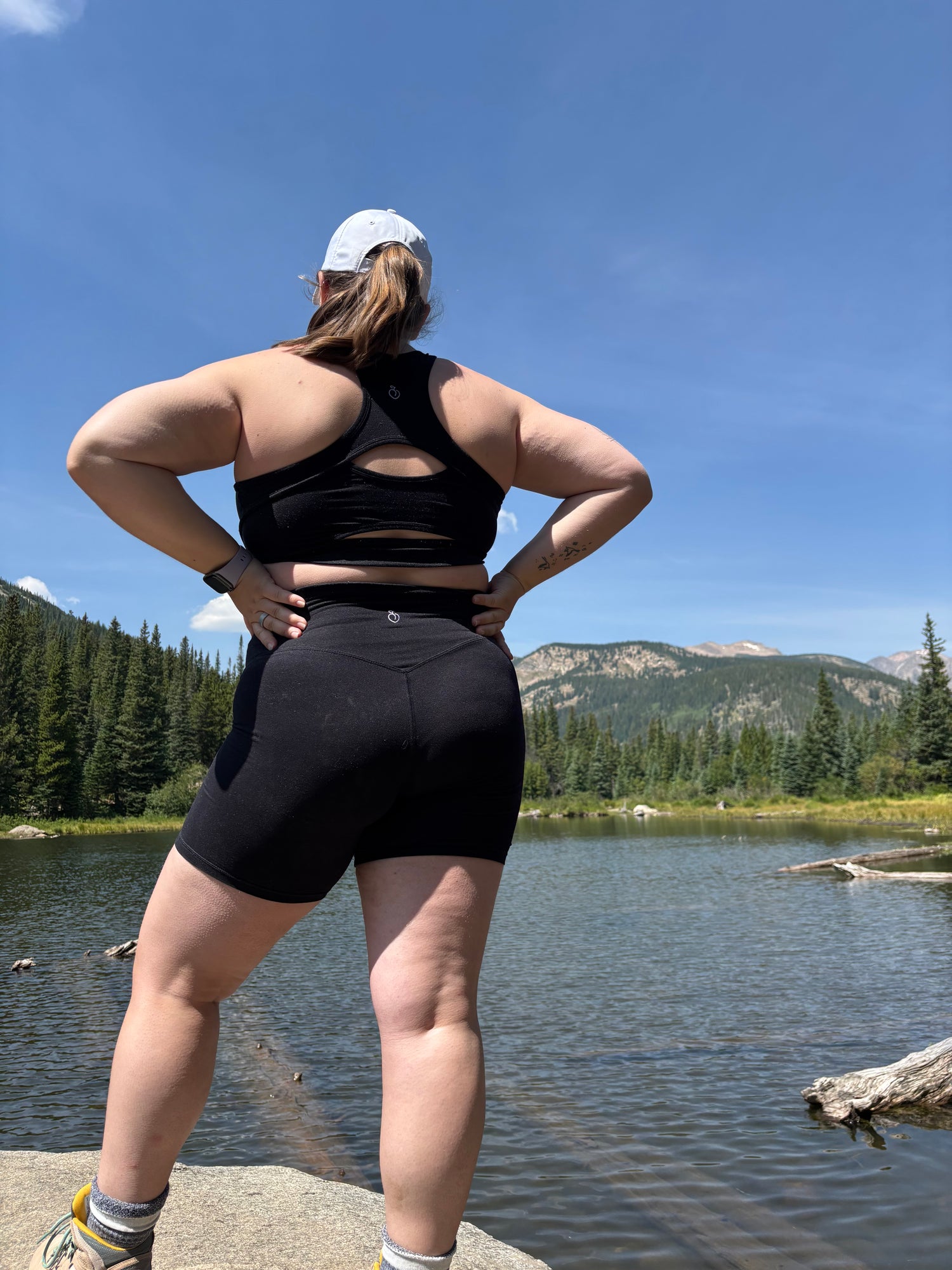 Person stretching outdoors by a lake with mountains in the background
