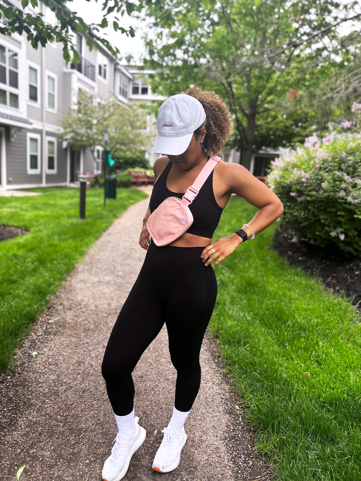 Woman wearing full Signature Set of black legging and bra, Everyday Cap in White, Classic Crew socks, and Crossbody bag in pink