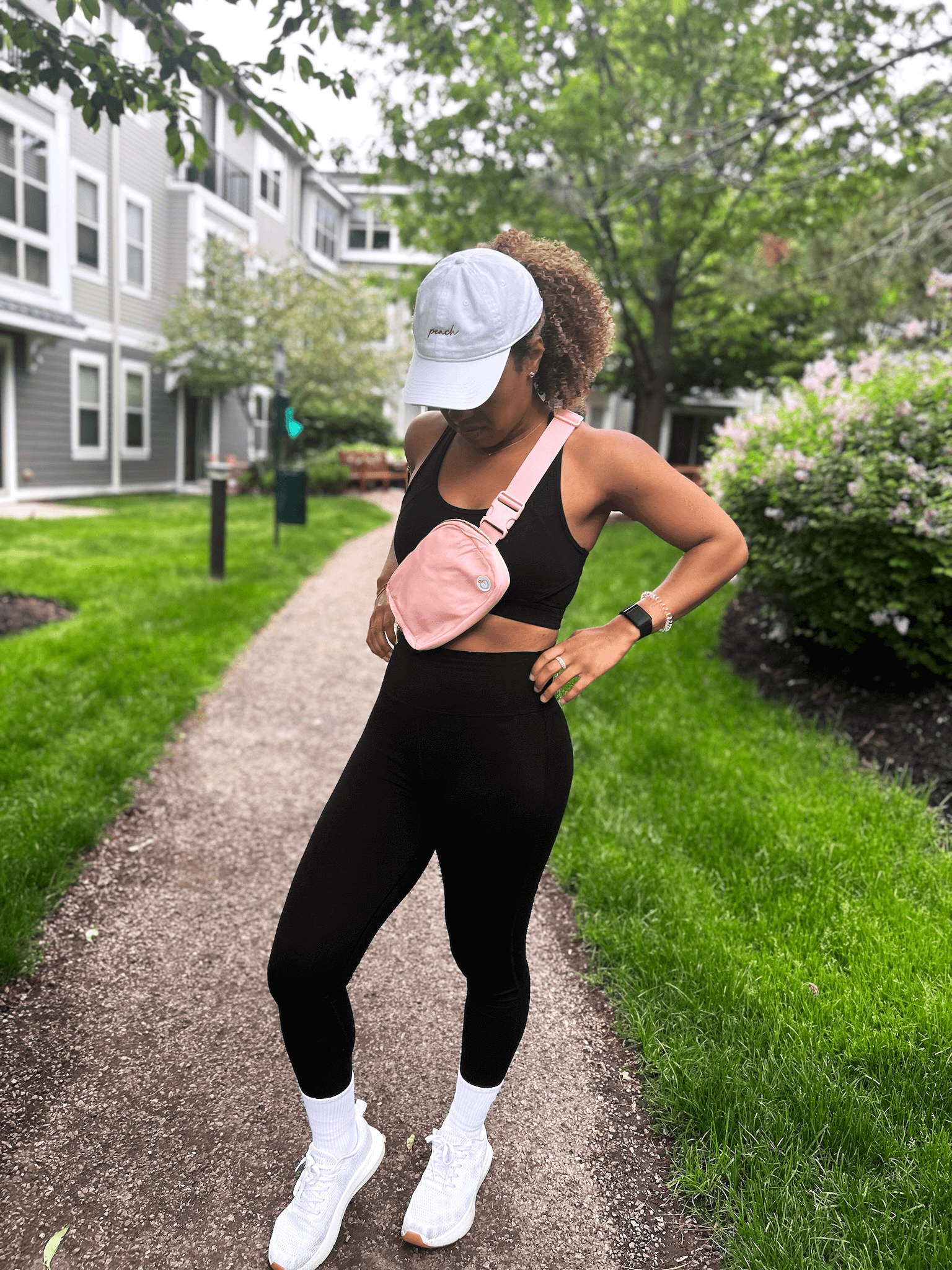 Woman wearing full Signature Set of black legging and bra, Everyday Cap in White, Classic Crew socks, and Crossbody bag in pink