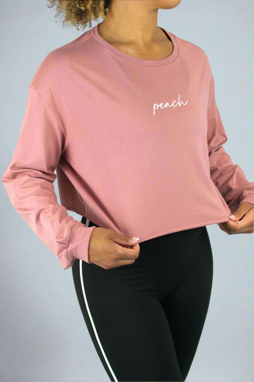 Person wearing a pink long-sleeve shirt with 'peach' text on a light gray background