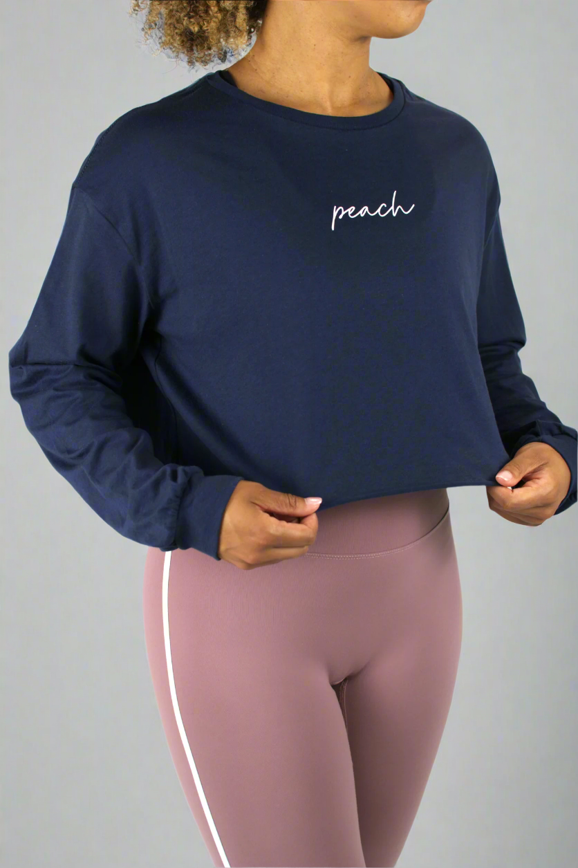 Person wearing a navy sweatshirt with 'peach' text and pink leggings on a white background