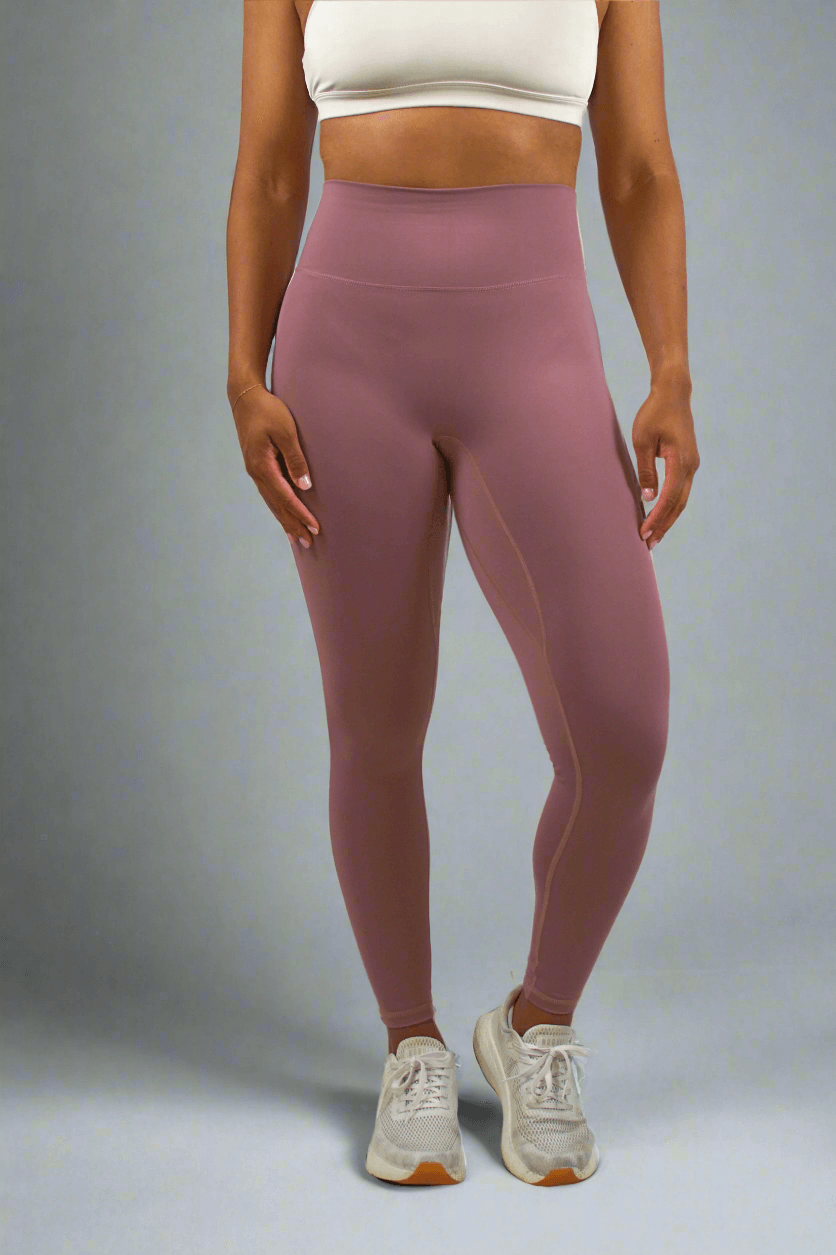 Person wearing mauve leggings and a white crop top on a white background