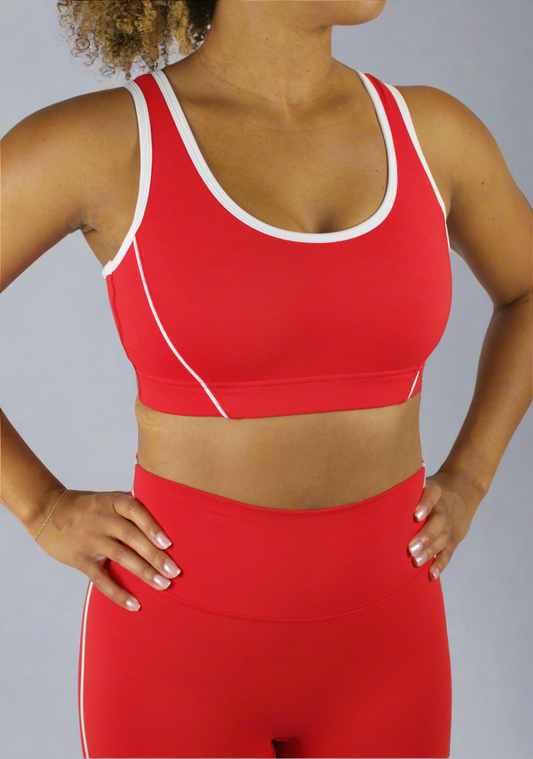 Person wearing a red sports bra and leggings set on a gray background