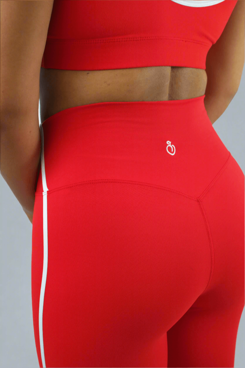 Red athletic leggings with a white logo on a gray background