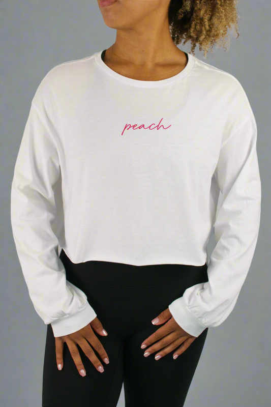 Person wearing a white long-sleeve shirt with 'peach' text in pink on a gray background