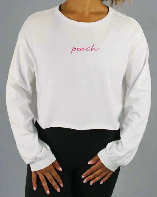 Person wearing a white long-sleeve shirt with 'peach' text in pink on a gray background