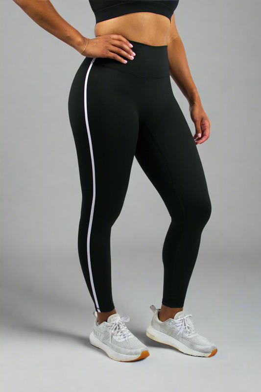 Person wearing black leggings with white stripes on a white background