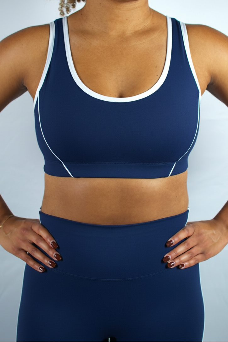 Person wearing a navy blue sports bra and leggings set against a light gray background