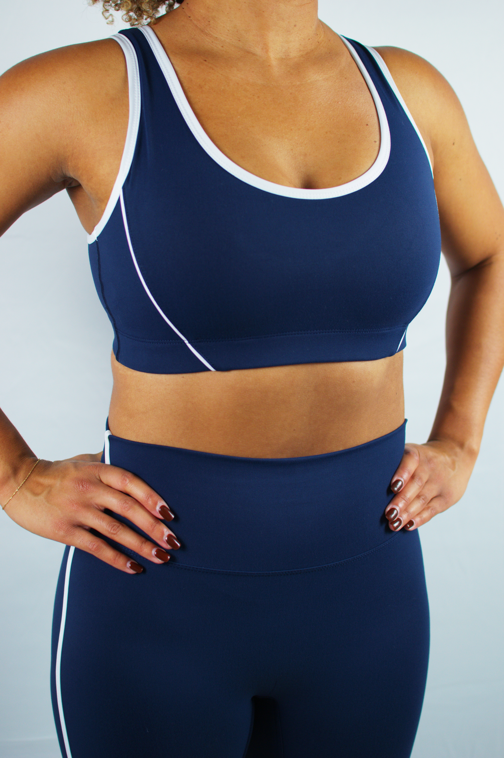 Person wearing a navy blue sports bra and leggings set on a light gray background