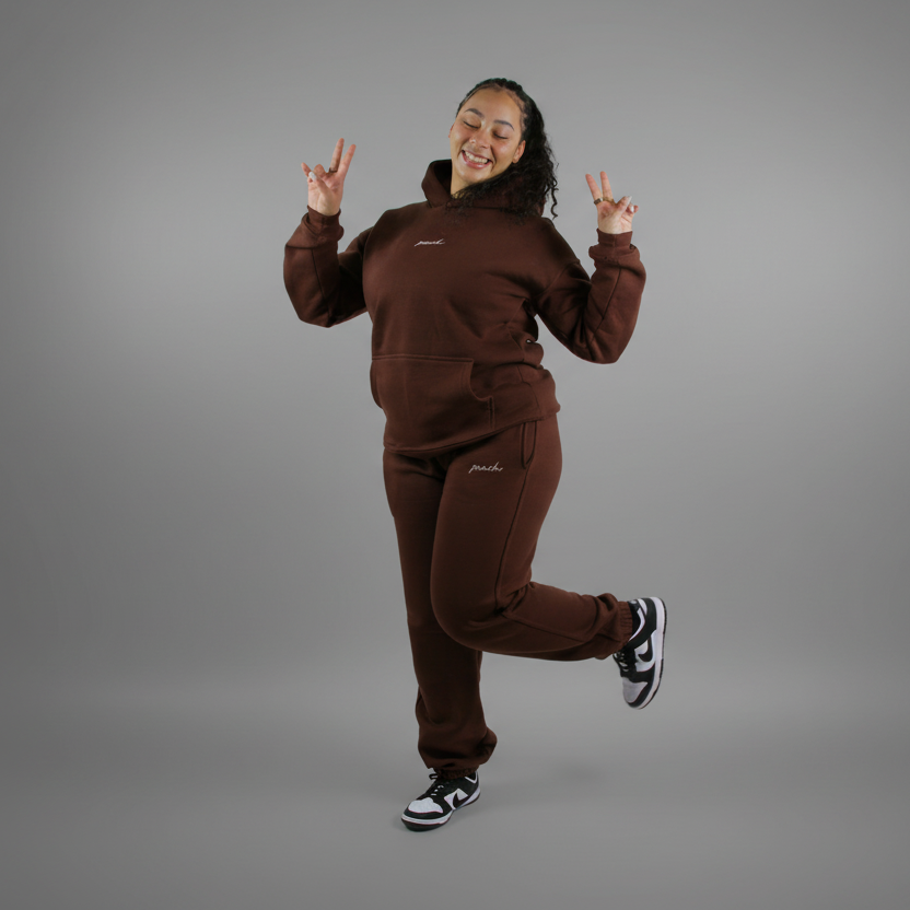 Person wearing a brown tracksuit posing against a white background