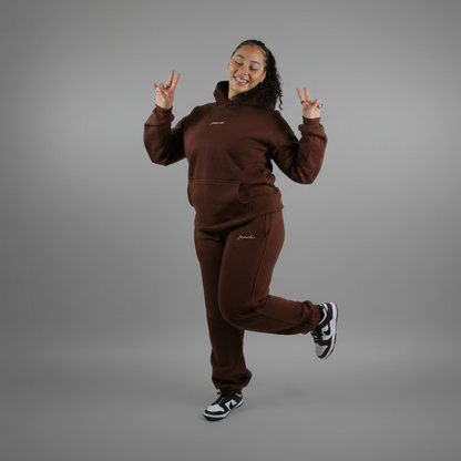 Person wearing a brown tracksuit posing against a white background