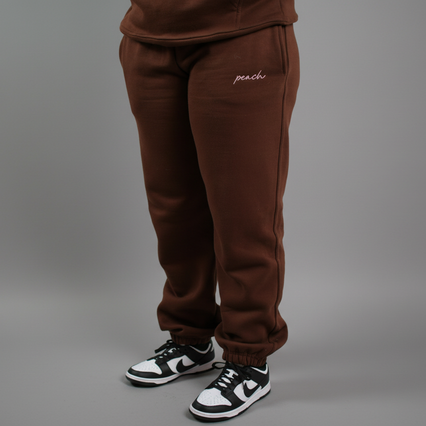 Brown sweatpants with 'peach' embroidery on a white background