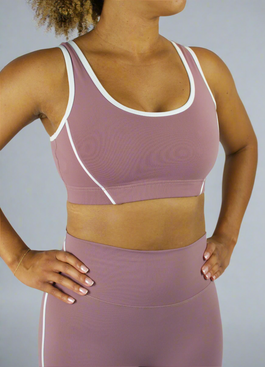 Person wearing a mauve sports bra and leggings set on a plain background