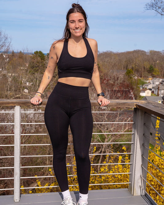 Woman in black athletic wear standing on a rooftop with a scenic background