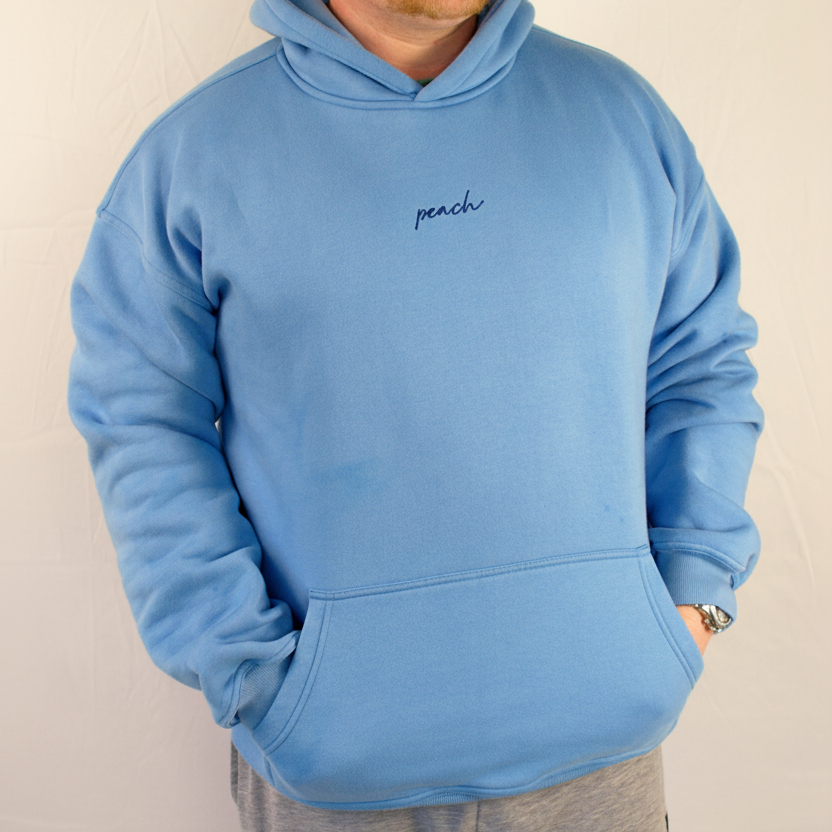 Person wearing a blue hoodie with 'peach' text on a plain background