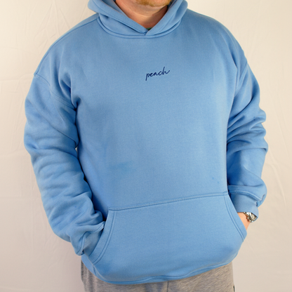 Person wearing a blue hoodie with 'peach' text on a plain background