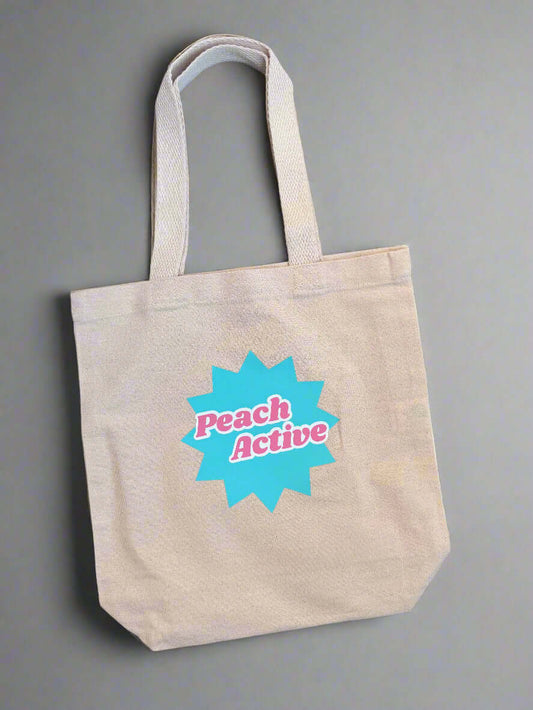 Beige tote bag with 'Peach Active' logo on a wooden surface