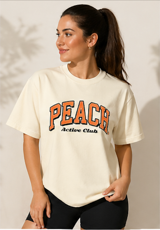 Woman wearing a cream t-shirt with 'Peach Active Club' text against a neutral background