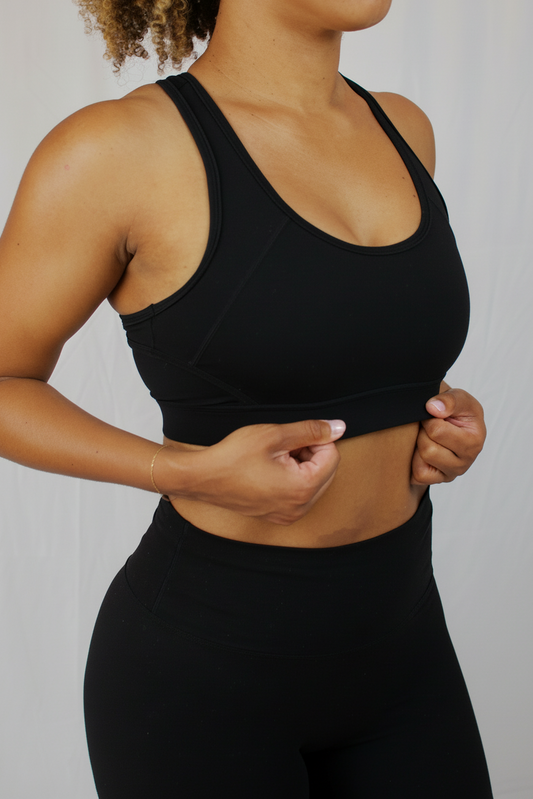 Person wearing a black sports bra and leggings against a plain background