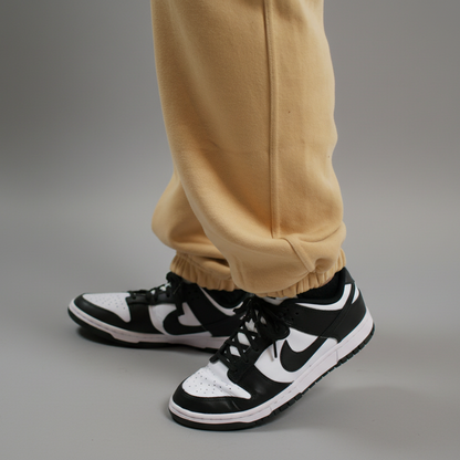 Black and white sneakers with a logo worn with beige pants on a light background