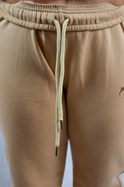 Close-up of beige sweatpants with a drawstring on a light gray background