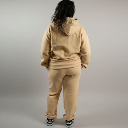 Person wearing a beige tracksuit against a white background