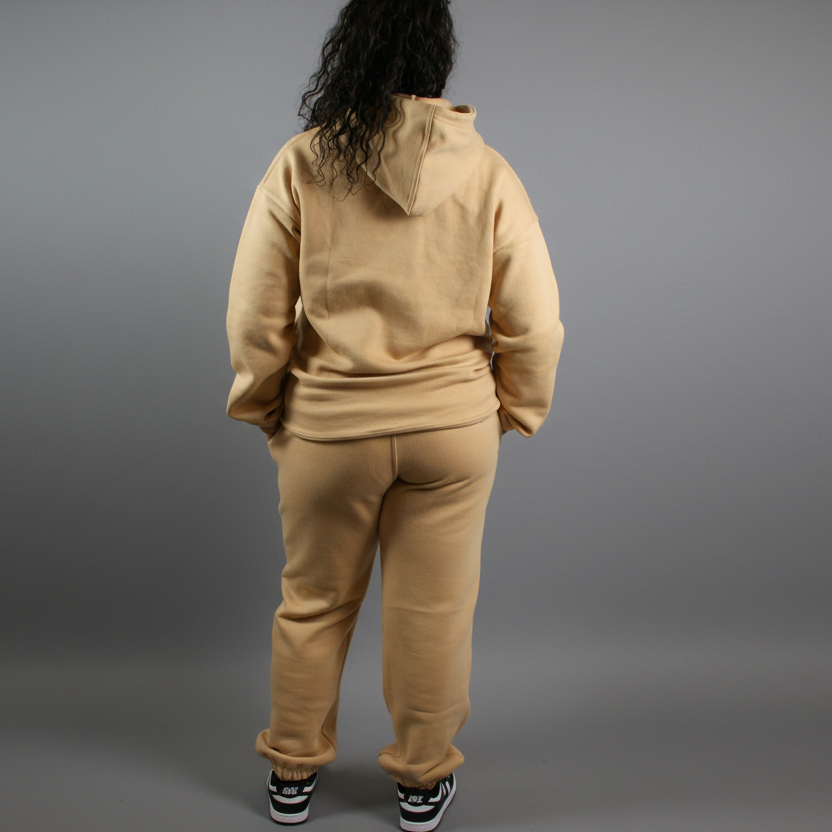 Person wearing a beige tracksuit against a white background