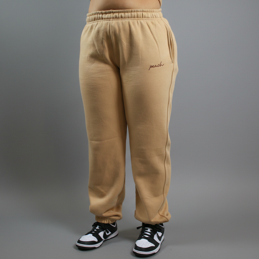 Beige sweatpants with 'peach' embroidery on a white background